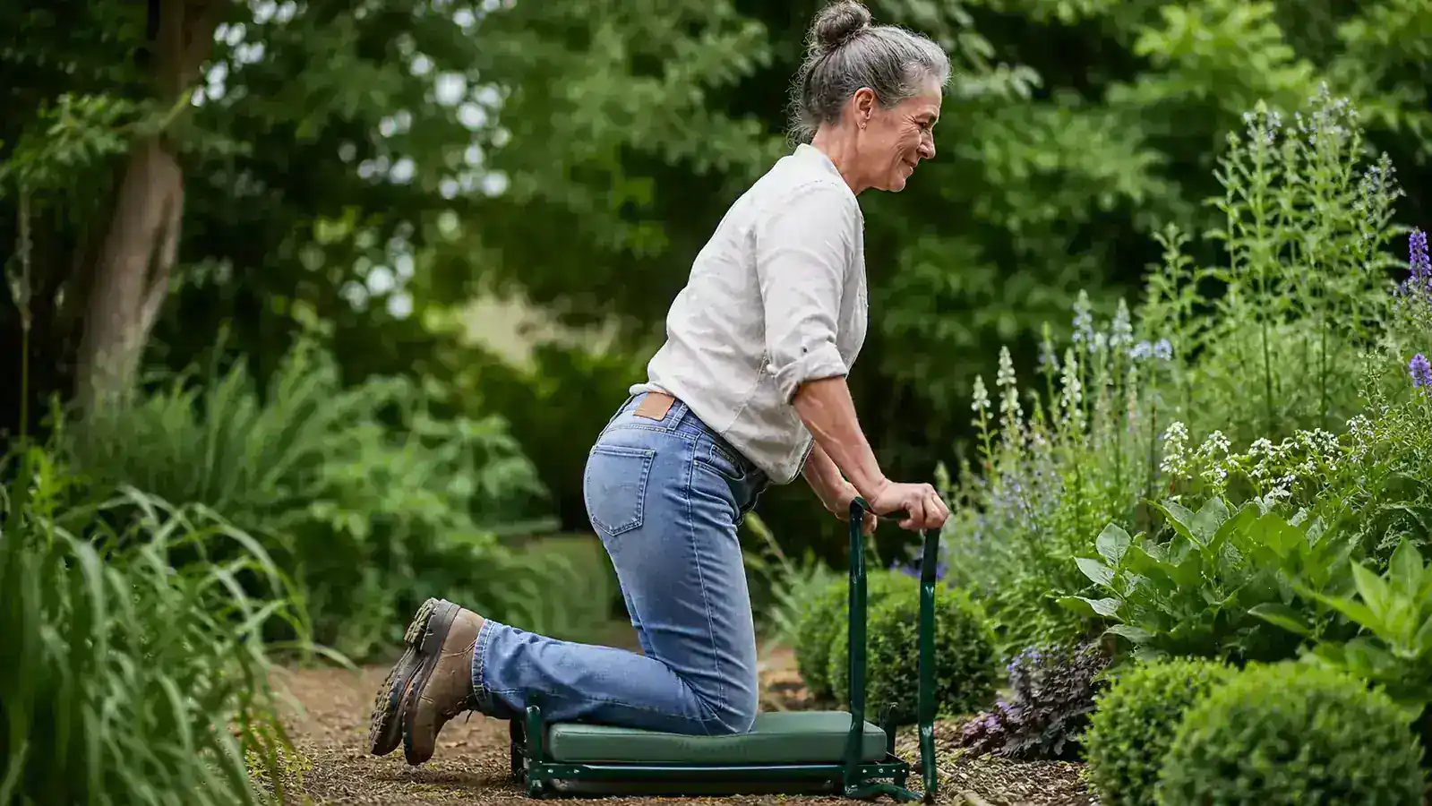 Gardener pressing down on support handles to push herself up from a kneeling position in the garden